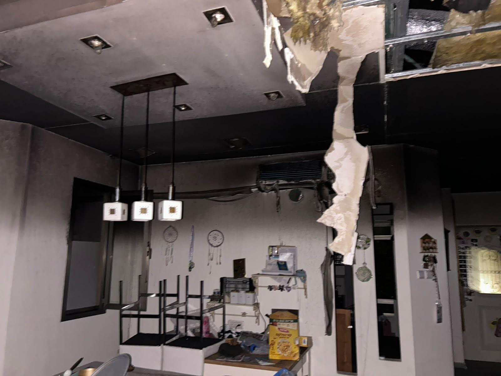 The living room after the fire — the ceiling torn open, soot covering the walls and belongings